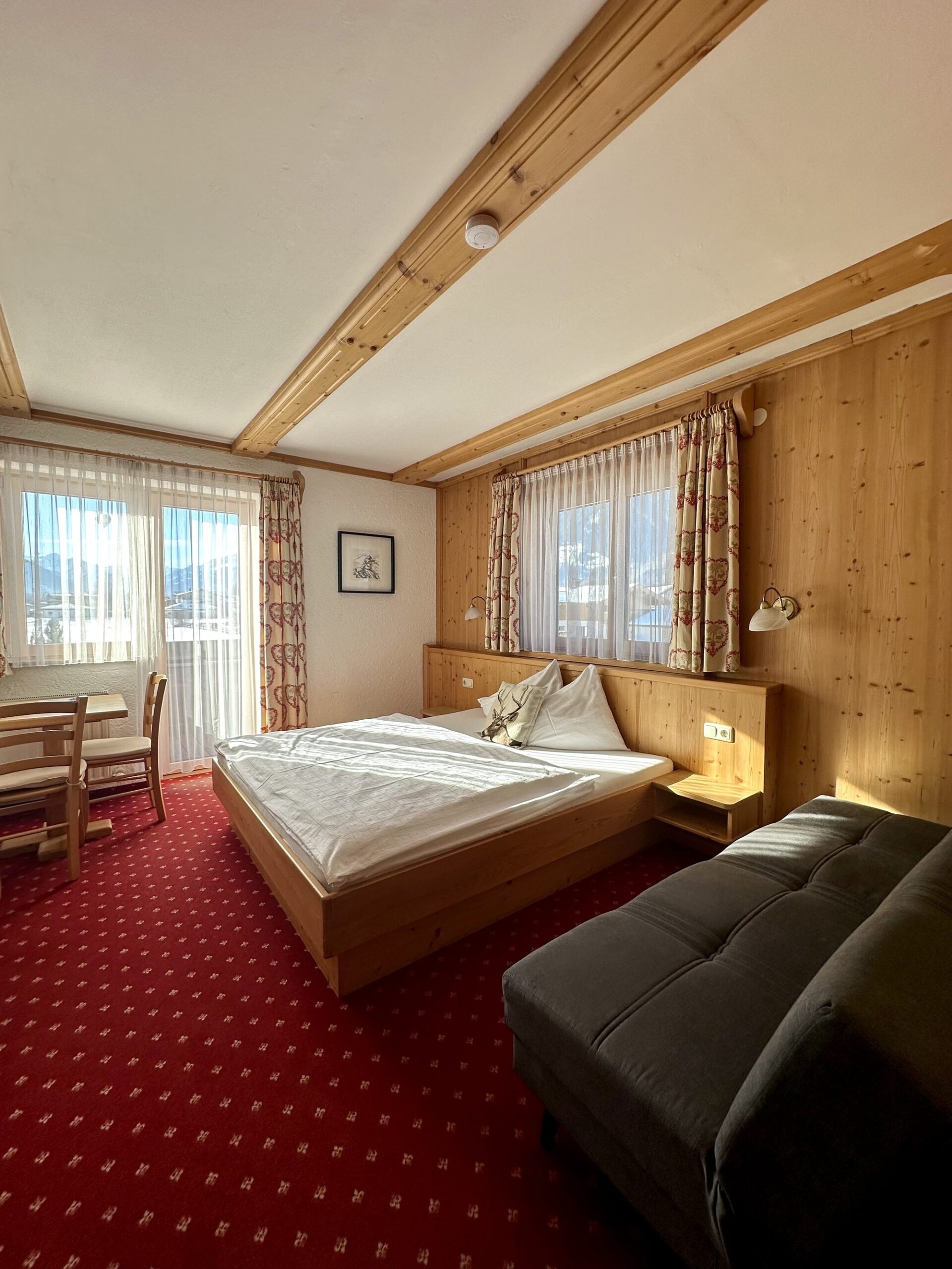 Doppelzimmer mit Sofa und Balkon im Landhaus Quehenberger in Maishofen