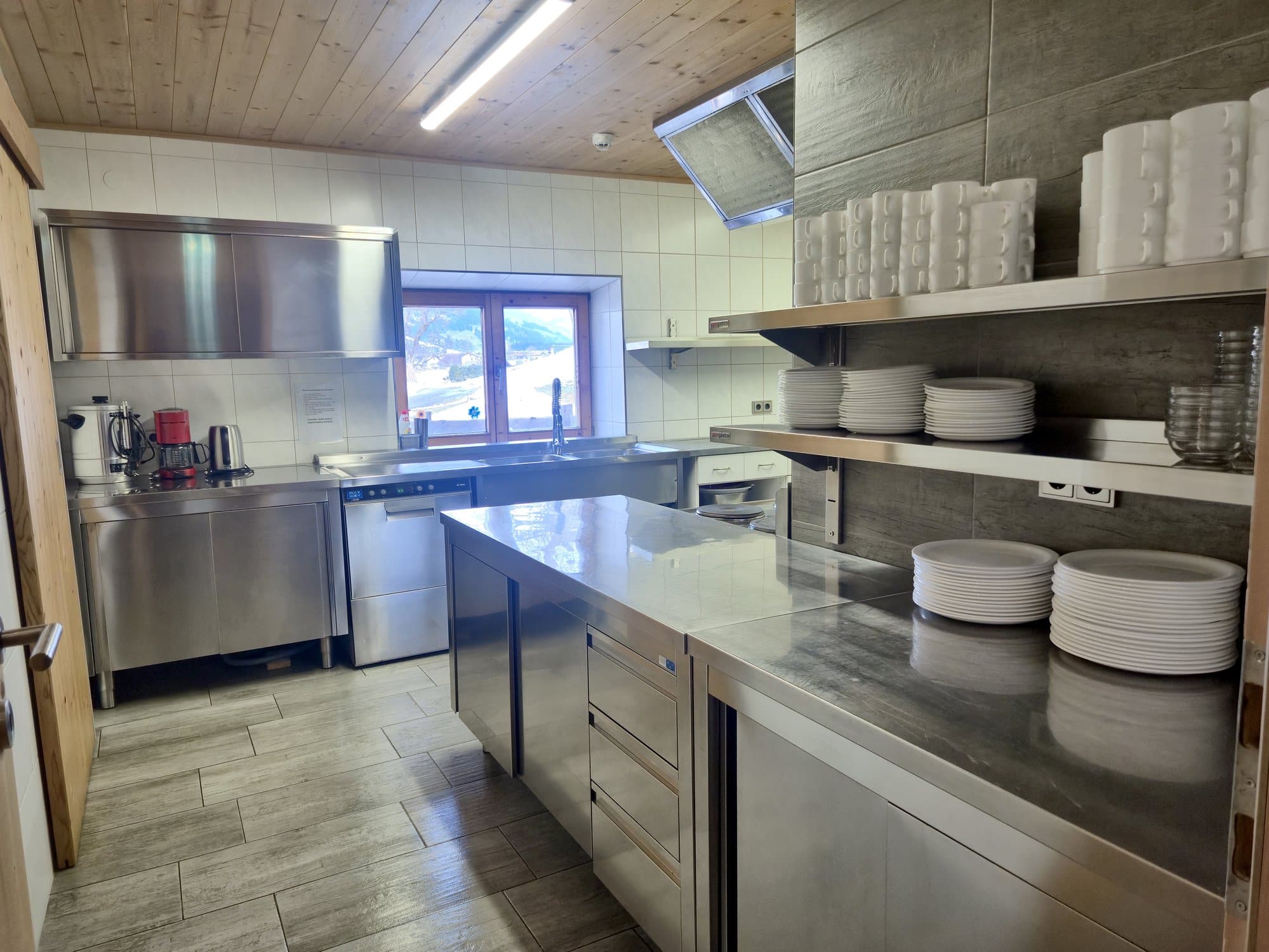 Professionelle Großküche im Selbstversorgerhaus Maishofen mit Edelstahl-Arbeitsflächen und umfangreichem Geschirr
