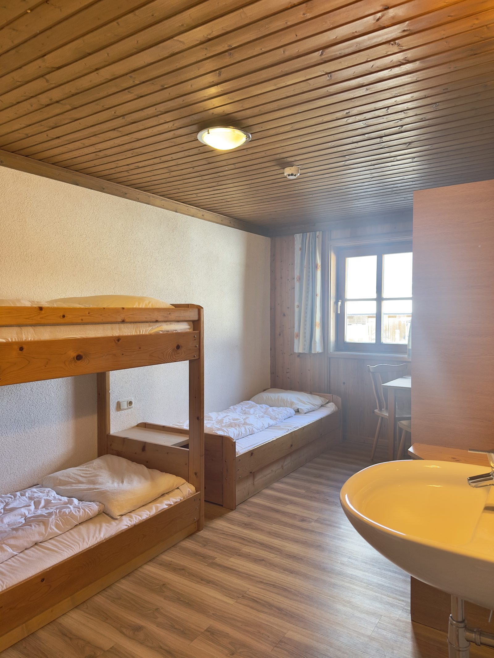 Mehrbettzimmer mit Stockbett und Waschbecken im Selbstversorgerhaus Maishofen im Salzburger Land