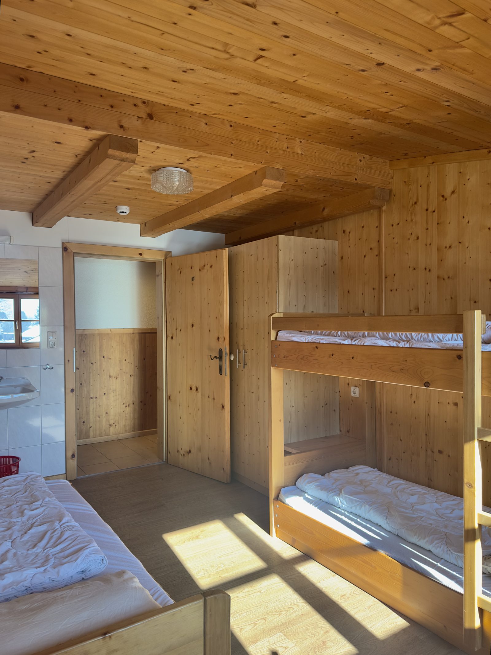 Mehrbettzimmer mit Stockbett und viel Holz im Selbstversorgerhaus Maishofen – Gruppenunterkunft im Salzburger Land